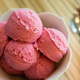 Bowl of raspberry sorbet scoops next to spoon